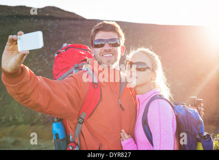 Coppia felice di prendere foto di se stessi con smart phone all'aperto, prendendo un 'selfie' Foto Stock