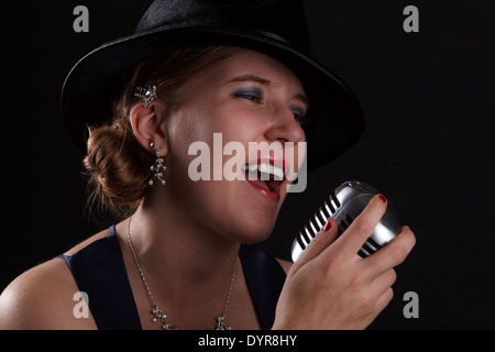 Bellissimo canto jazz donna con fedora e stile retrò microfono Foto Stock