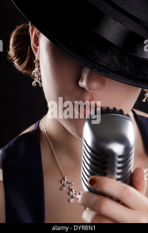 Bellissimo canto jazz donna con fedora e stile retrò microfono Foto Stock