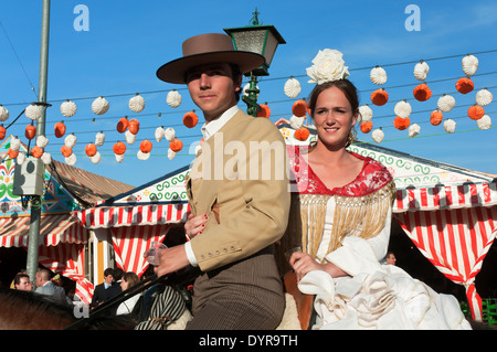 Fiera di Aprile, giovane coppia di piloti in sella a cavallo con i tradizionali costumi di flamenco, Siviglia, regione dell'Andalusia, Spagna, Europa Foto Stock