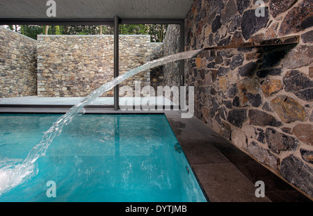 Piscina interna con fontana e flusso di acqua e pietra circondano Foto Stock