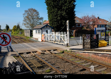 Stazione Poppleton master protezione di un passaggio a livello gate prima un treno arriva alla stazione in una giornata di sole. Foto Stock