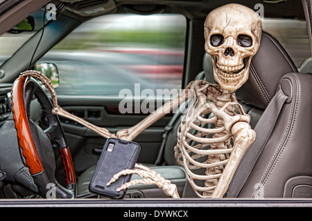Uno scheletro dietro al volante di un SUV, distratti dal suo telefono cellulare. Egli è anche non indossare una cintura di sicurezza. Foto Stock