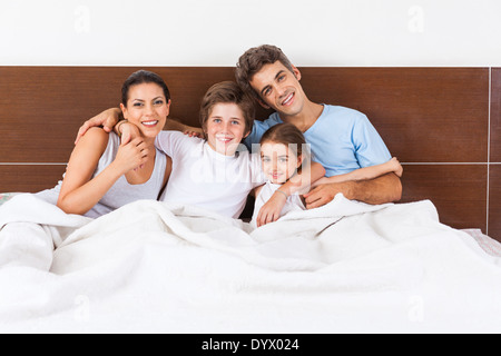 La famiglia sul letto matrimoniale, giovane i genitori di bambini Foto Stock