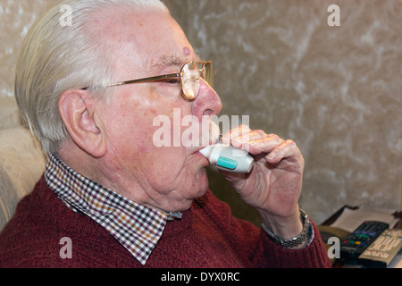 Uomo vecchio usando un inalatore o puffer, per alleviare i problemi respiratori. Foto Stock