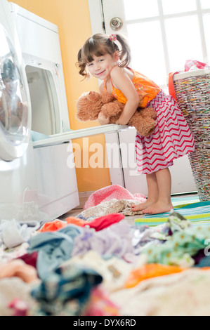 Una bambina abbraccia un orsacchiotto che ella ha rimosso dalla lavanderia pulita. Foto Stock