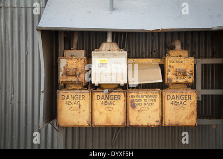 Una serie di giallo di acciaio arrugginito box alimentatore al di fuori di una fabbrica Foto Stock