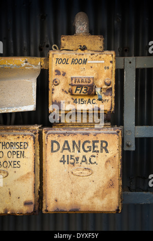 Una serie di giallo di acciaio arrugginito box alimentatore al di fuori di una fabbrica Foto Stock