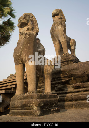 Una scimmia si siede sul retro di una statua a Angkor Wat, Sito Patrimonio Mondiale dell'UNESCO. Siem Reap, Cambogia Foto Stock