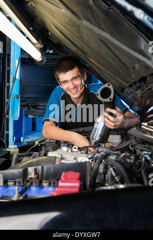 Apprendista meccanico sotto il cofano per auto Foto Stock