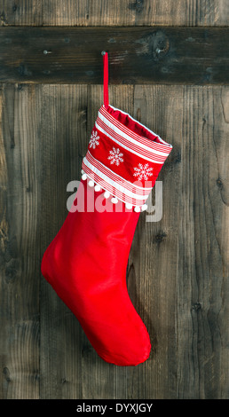 Calza rossa con i fiocchi di neve per Santa regali appesi sopra in legno rustico sfondo. Calza di Natale Foto Stock