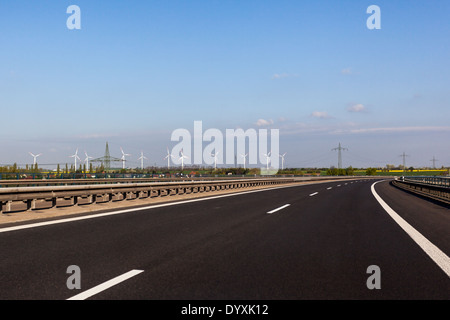 In autostrada è possibile vedere in lontananza una fattoria eolica Foto Stock