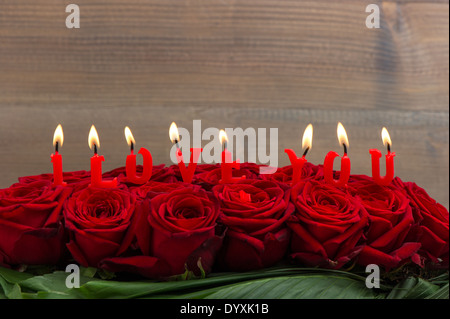 Rose rosse e candele accese facendo ti amo. Festive floreale. messa a fuoco selettiva Foto Stock