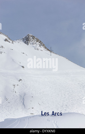 Picco di montagna e le piste da sci completo con un segno pubblicità Les Arcs. Foto Stock