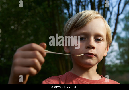 Ritratto di bambino ragazzo biondo Stretching Bubble Gum in bocca Foto Stock