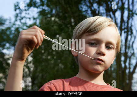 Ritratto di bambino ragazzo biondo Stretching Bubble Gum in bocca Foto Stock