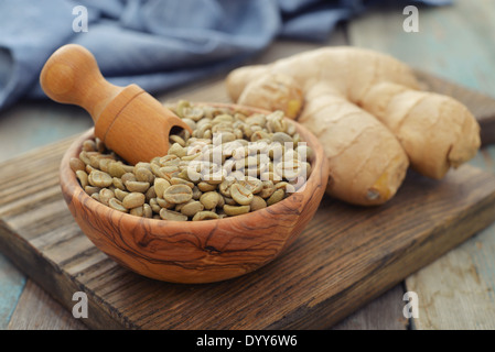 Chicchi verdi di caffè nella ciotola di legno con lo zenzero Foto Stock