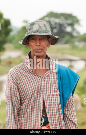 Un vecchio uomo tailandese, un agricoltore, mucca herder. Indossa un vecchio plaid camicia e un soldato bim hat, sorridente. Foto Stock