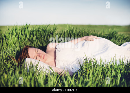 Giovane donna che dorme sul morbido cuscino in fresco di erba di primavera