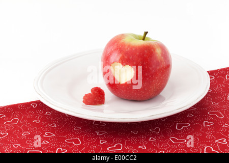 Red apple con un cuore taglio sagomato-out su una tovaglia Foto Stock