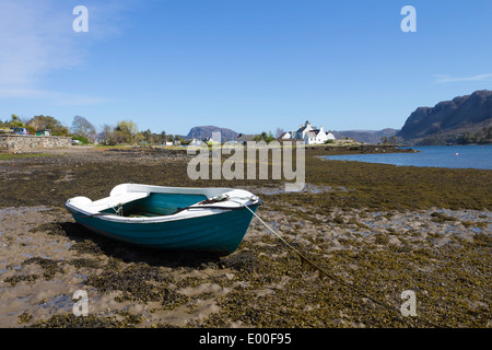 Barca ormeggiata sulla spiaggia con la bassa marea in Plockton Harbour costa ovest della Scozia UK Foto Stock