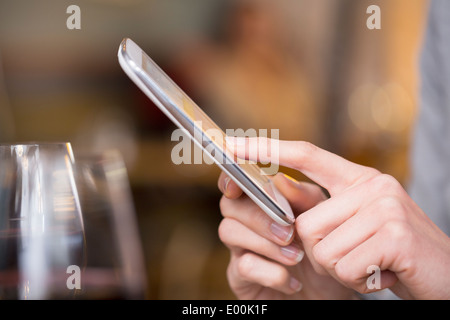 Femmina pub allo smartphone i messaggi di testo sms dita messgae pub e-mail Foto Stock