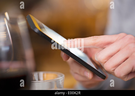 Femmina pub allo smartphone i messaggi di testo sms dita messgae pub e-mail Foto Stock