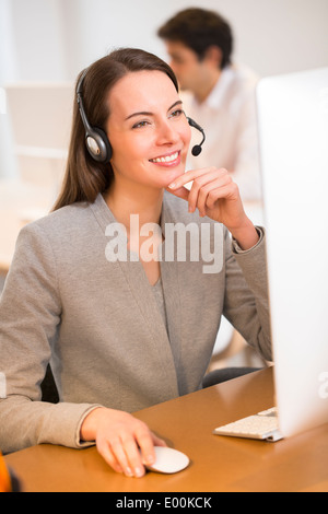 Donna sorridente piuttosto desk ritratto delle cuffie Foto Stock