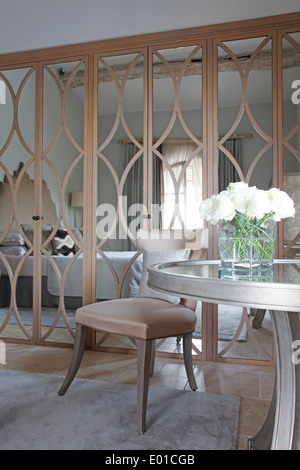 Specchio modellato gli sportelli degli armadi in camera per ospiti di St Tropez villa con tavola circolare con rose bianche in primo piano Foto Stock