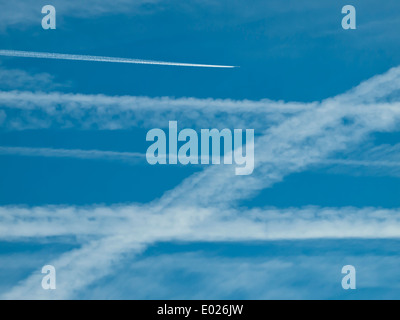 Configurazione di molte contrails/vapori delle scie di aerei nel cielo blu. Foto Stock