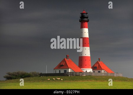 Foto della rossa e bianca a strisce westerheversand faro con la tempesta del Cielo e nubi, penisola di eiderstedt, Germania Foto Stock