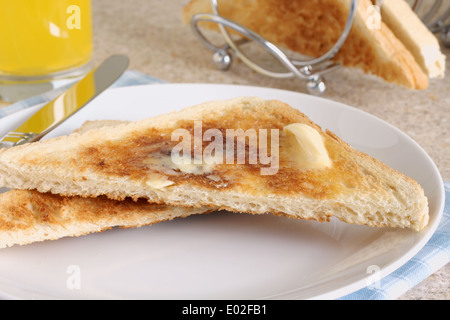 Pane bianco, toast con burro di fusione di arancia e un toast rack Foto Stock