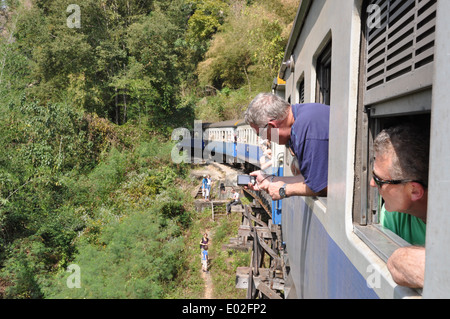 I turisti sporgersi delle finestre di un treno su la Thai - Birmania ferroviarie, Thailandia. Foto Stock