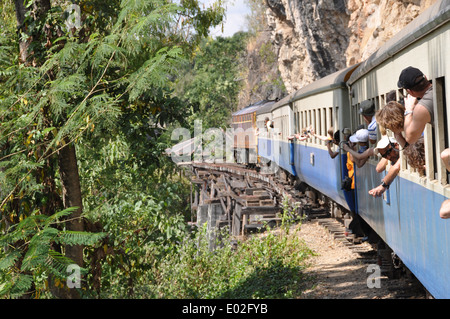 I turisti sporgersi delle finestre di un treno su la Thai - Birmania ferroviarie, Thailandia. Foto Stock