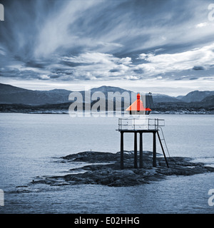 Red norvegese torre faro sul mare rocce sotto il cielo tempestoso Foto Stock