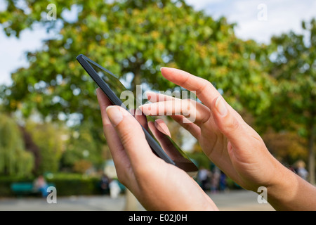 Close-up femmina telefono mobile alberi Panchetta outdoor messaggi sms e-mail Foto Stock
