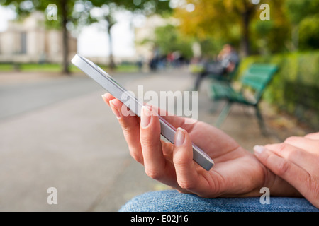 Close-up femmina telefono mobile alberi Panchetta outdoor messaggi sms e-mail Foto Stock