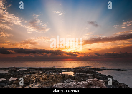 Spiaggia rocciosa e Sky con Sunray sulla Mattina nuvoloso Foto Stock