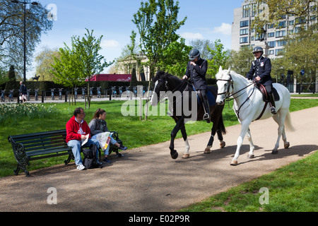 Due metropolitan polizia montata a cavallo attraverso il parco verde di Londra. Foto Stock