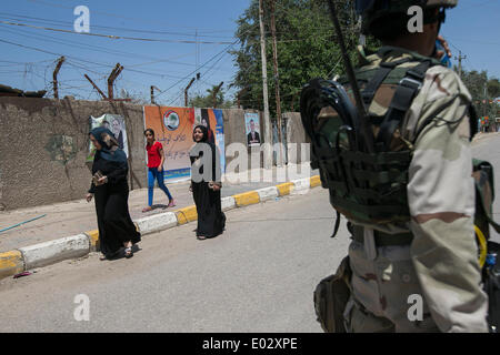 Baghdad in Iraq. 30 apr 2014. Popolo iracheno a piedi passato le forze di sicurezza i membri a Baghdad, Iraq, 30 aprile 2014. Dieci persone sono state uccise e 22 altri feriti in attacchi separati di bersagliamento di centri di polling in Iraq il Mercoledì, la polizia ha detto. Credito: cui Xinyu/Xinhua/Alamy Live News Foto Stock