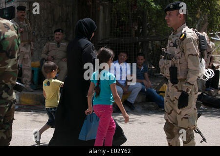 Baghdad in Iraq. 30 apr 2014. Una donna con i suoi bambini a piedi passato le forze di sicurezza i membri di guardia al di fuori di un punto di polling a Baghdad, Iraq, 30 aprile 2014. Dieci persone sono state uccise e 22 altri feriti in attacchi separati di bersagliamento di centri di polling in Iraq il Mercoledì, la polizia ha detto. Credito: cui Xinyu/Xinhua/Alamy Live News Foto Stock