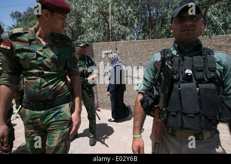 Baghdad in Iraq. 30 apr 2014. Una donna cammina passato le forze di sicurezza i membri di guardia al di fuori di un punto di polling a Baghdad, Iraq, 30 aprile 2014. Dieci persone sono state uccise e 22 altri feriti in attacchi separati di bersagliamento di centri di polling in Iraq il Mercoledì, la polizia ha detto. Credito: cui Xinyu/Xinhua/Alamy Live News Foto Stock