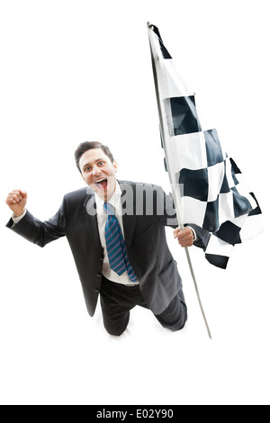 Un giovane imprenditore in ginocchio isolato su uno sfondo bianco sventola una bandiera a scacchi Foto Stock