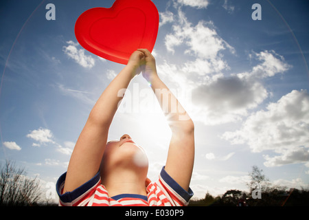 Un bambino tenendo un cuore rosso forma. Foto Stock