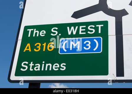 British cartello stradale sulla approccio alla rotatoria a dare indicazioni per il sud-ovest, Staines e l'autostrada M3 Foto Stock