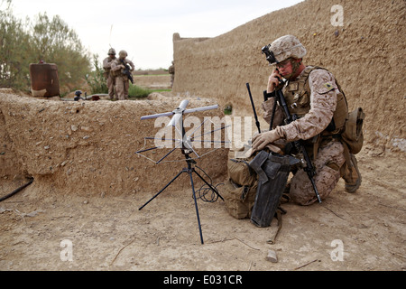 US marina il sergente Steven Olson parla attraverso il telefono satellitare durante un'operazione di compensazione missione 25 aprile 2014 nel villaggio di Larr, provincia di Helmand, Afghanistan. Foto Stock