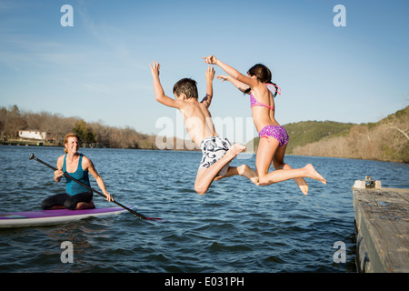 Due bambini saltando in acqua da un molo. Foto Stock