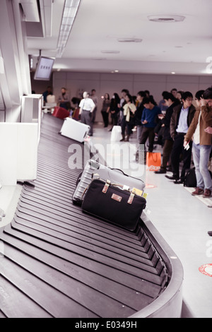 Persone in attesa per i loro bagagli all'Aeroporto Internazionale Narita reclamo bagagli trasportatore a giostra, Giappone Foto Stock