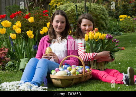 Uovo di Pasqua Caccia ragazze con le loro uova di cioccolato e fiori di primavera Foto Stock