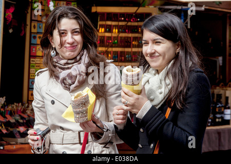 Due giovani donne che mangiano dolci cechi Trdelnik, un dessert tradizionale, Piazza della Città Vecchia, Praga, Repubblica Ceca mangiare Foto Stock